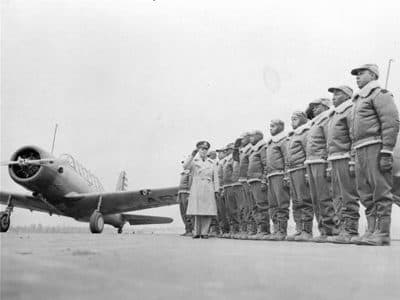 Airmen standing in formation beside a fighter aircraft